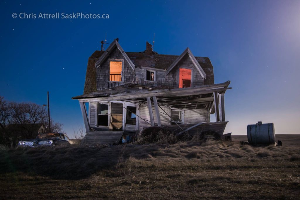 Abandoned house lit with orange lights at night.