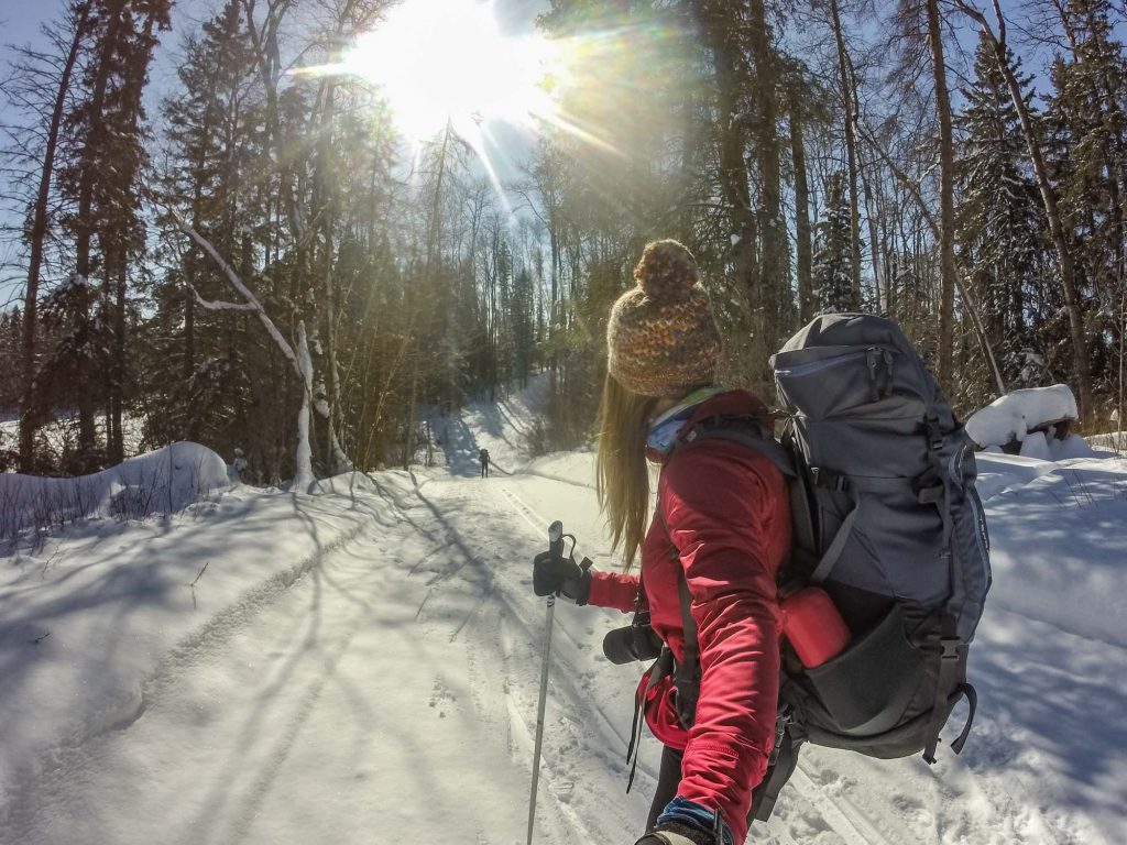 Woman on cross-country ski trails looking down snow covered trail.