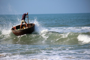 The motion of the fisherman navigating out through the waves in the traditional woven bamboo basket boats adds to the image 
