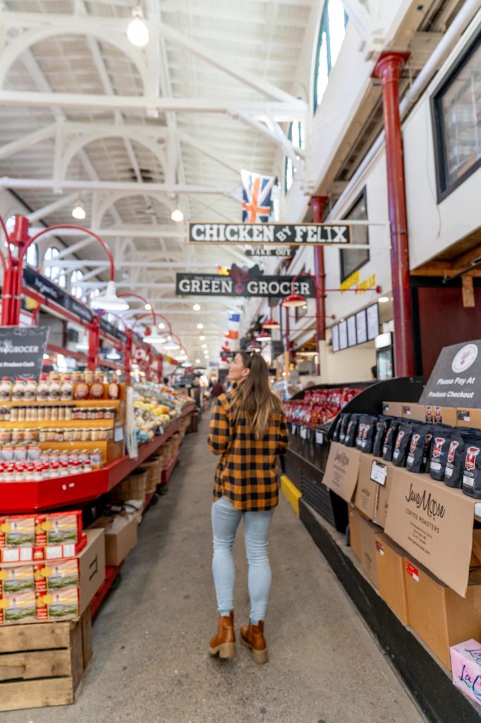 A woman in a yellow plaid shirt walking through a marketplace.