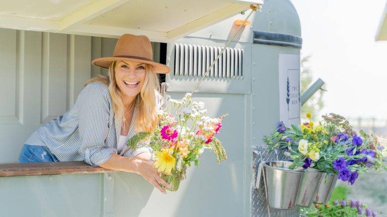 Smiling woman holding a bouquet of flowers in a flower truck