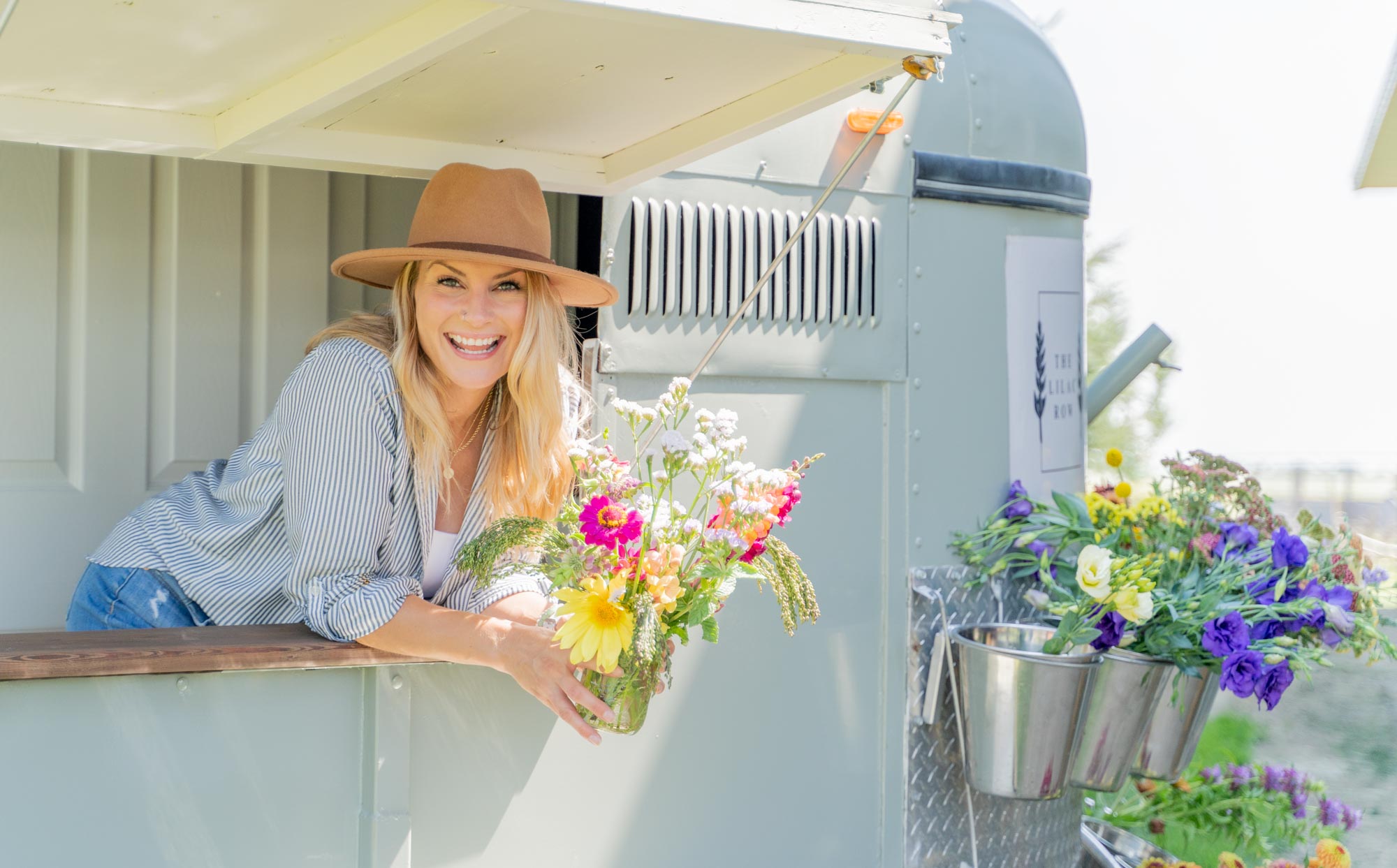 Smiling woman holding a bouquet of flowers in a flower truck