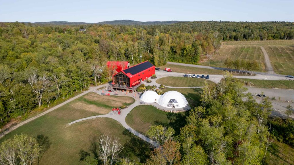Aerial view of a white dome tent and a red building with pathways leading to sitting areas.
